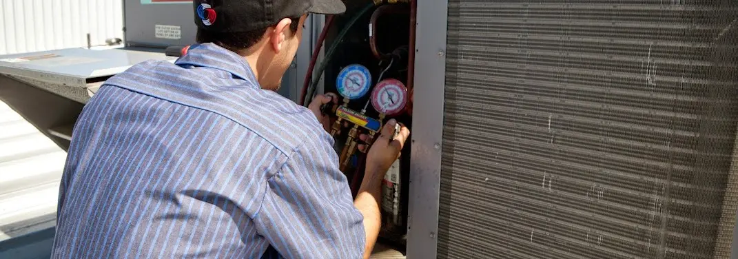 HVAC technician servicing a condenser unit in North Hanover